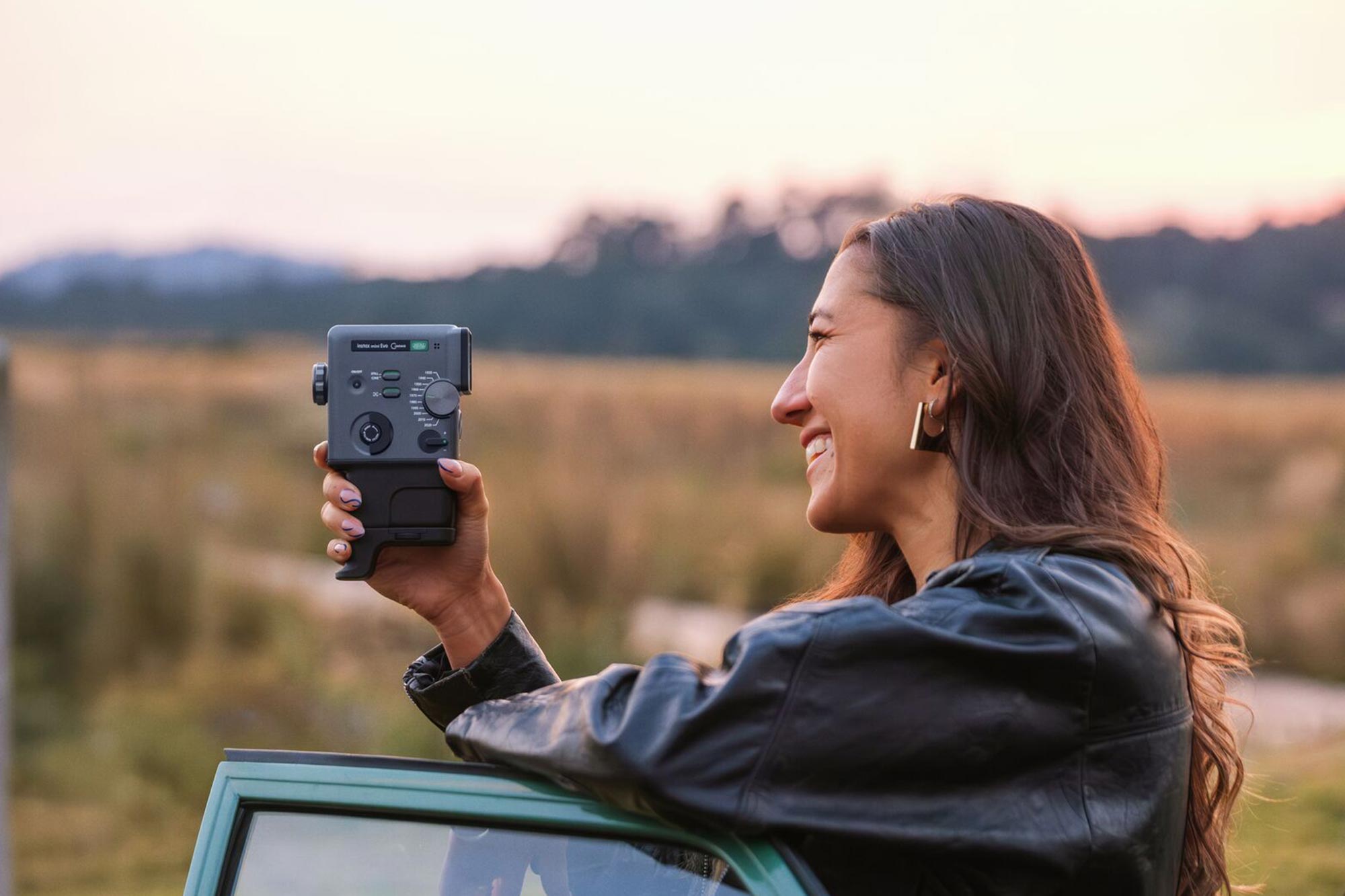 En kvinna filmar med Fujifilm instax Mini Evo Cinema vid ett fält